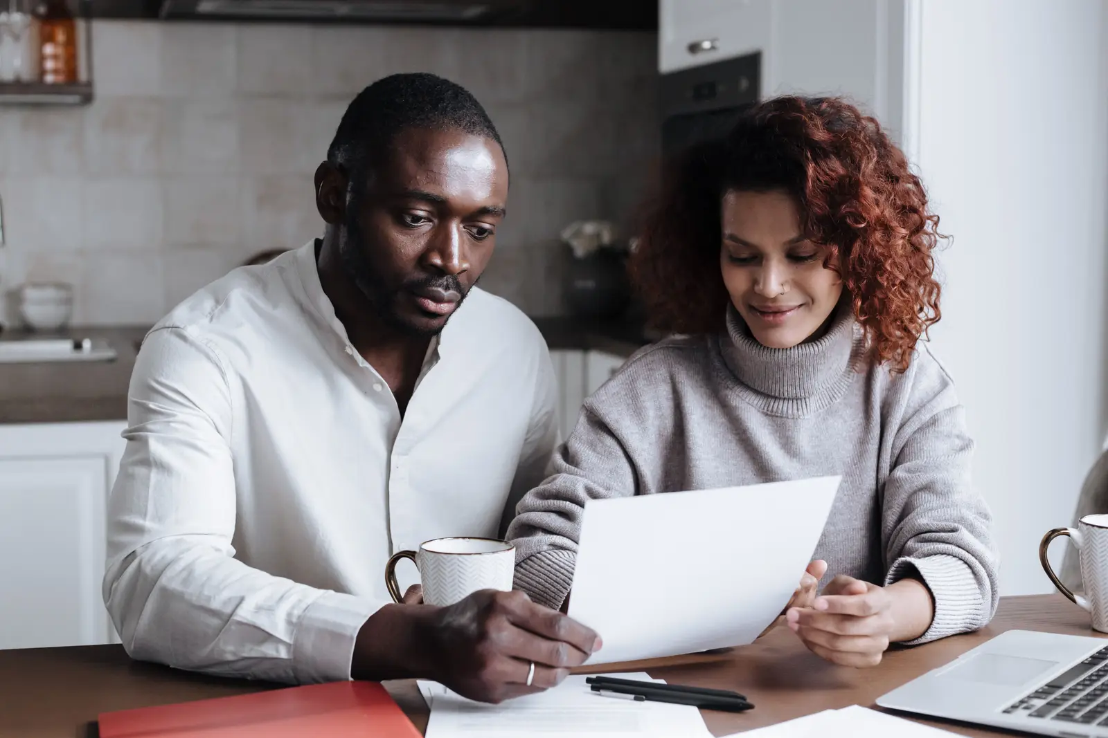 A couple reading through paperwork together at their kitchen table