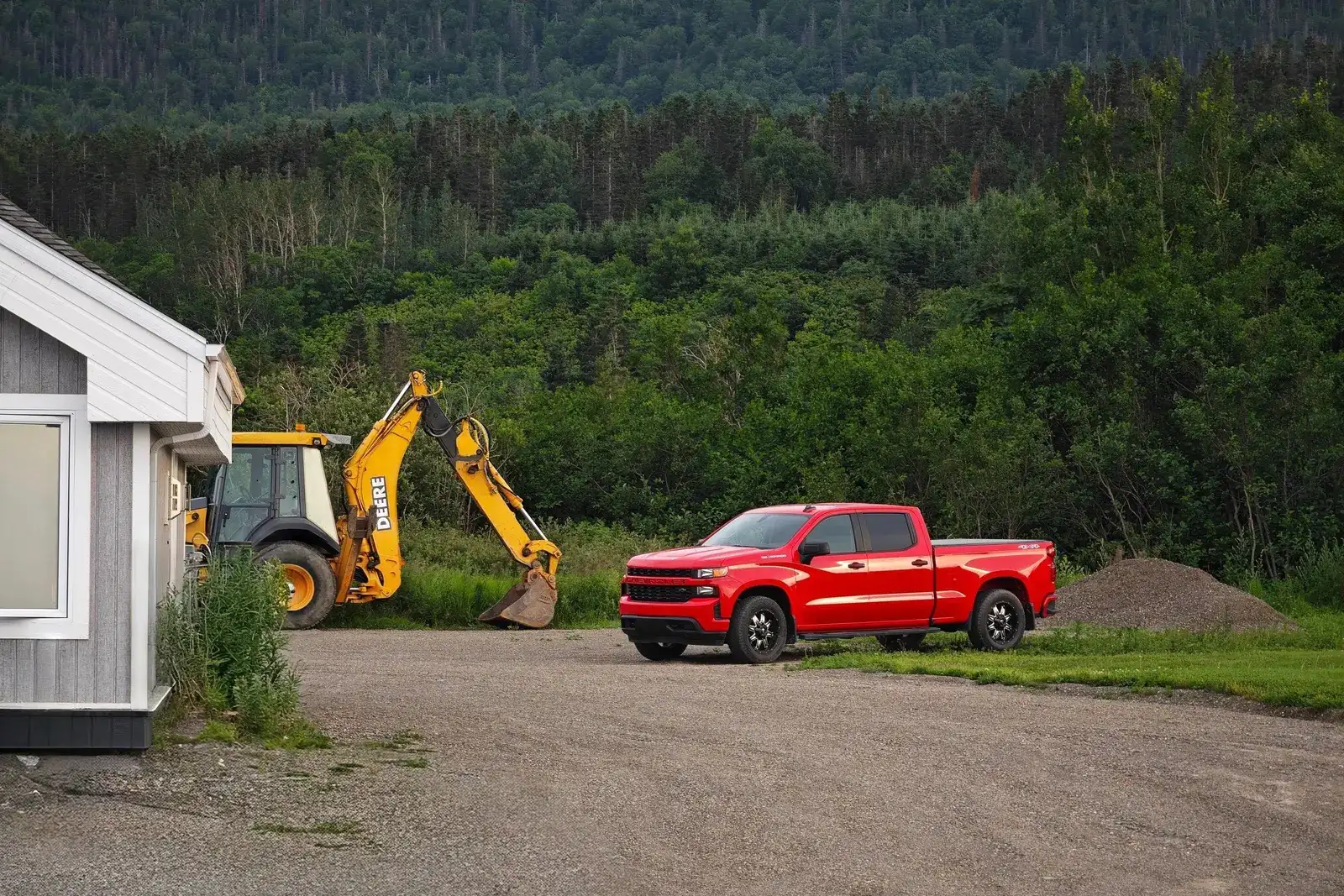 A red pickup truck and a backhoe at a contractor job site, a commercial auto and general liability risk