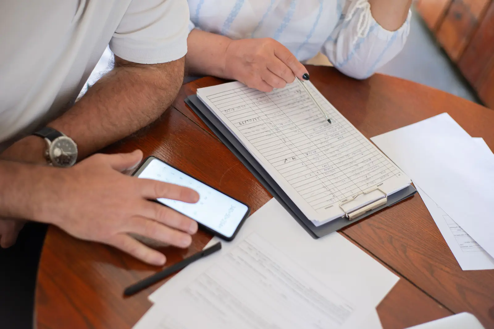 An older couple reviewing plan paperwork at a table with a phone and a clipboard