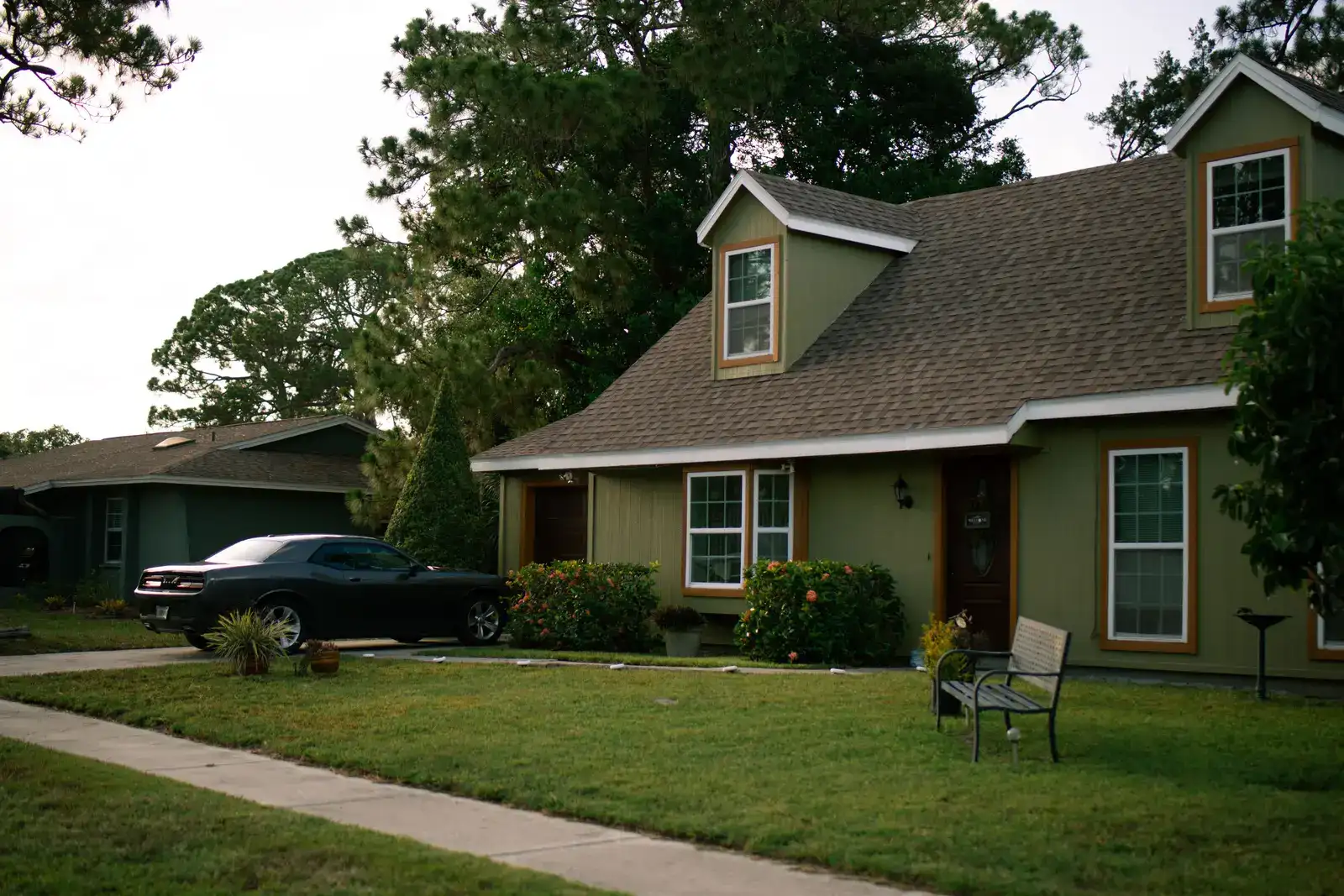 A suburban family home with a car in the driveway, the household behind an auto and home quote